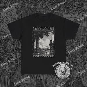 Może przedstawiać: Czarny T-shirt z nadrukiem graficznym górskiego krajobrazu i tekstem "The Mountains Are Calling And I Must Go".