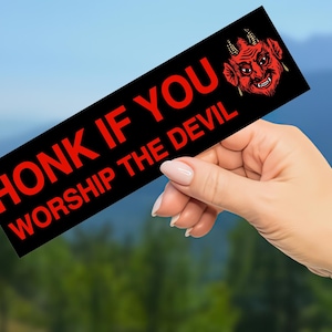 Puede incluir: Pegatina para parachoques negra y roja con el texto "HONK IF YOU WORSHIP THE DEVIL" y una ilustración de un diablo rojo.