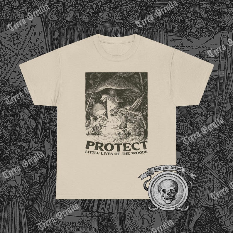 May include: Cream-colored t-shirt featuring a black and white illustration of a toad, mushroom, and small creature in a forest scene. The word "PROTECT" is printed above "LITTLE LIVES OF THE WOODS". A skull emblem is visible at the bottom right.