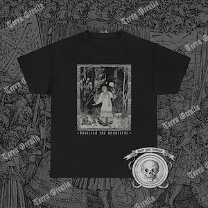 Puede incluir: Camiseta negra con un gráfico blanco de una mujer en un bosque. El texto "Vasilisa la Bella" está impreso debajo del gráfico. El texto "Conoce tu oscuridad" está impreso en un gráfico de calavera en la esquina inferior derecha.