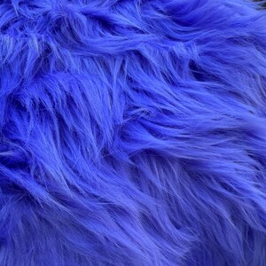 Può includere: Primo piano di un vibrante tessuto di finta pelliccia a pelo lungo in una sorprendente tonalità di blu. Il materiale morbido ha un aspetto morbido e strutturato con singole fibre visibili, creando un aspetto e una sensazione lussuosi. Ideale per progetti di artigianato o scopi decorativi.