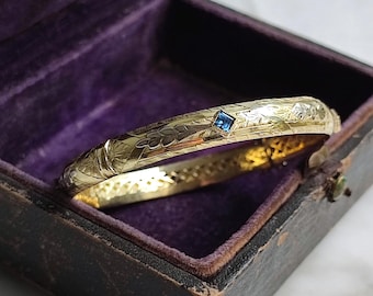 Antique rigid opening bangle bracelet in 18K yellow gold, floral motifs chiseled in 18K white gold and blue sapphires