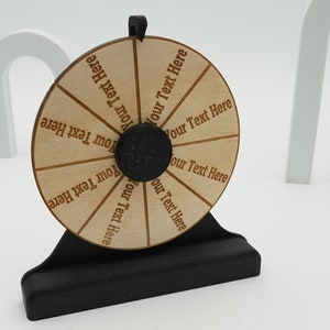 May include: A wooden spinning wheel with a black base. The wheel has eight sections, each with the text "Your Text Here" written on it.