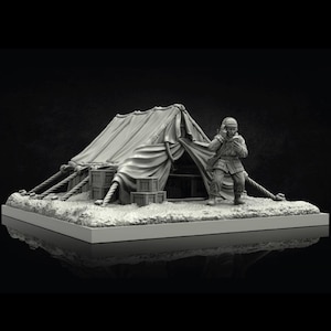 Puede incluir: Diorama en miniatura gris que representa una escena de campamento militar. Una tienda de campaña de lona está sostenida por cuerdas y cajas de madera. Una figura con uniforme militar está de pie cerca de la tienda, sosteniendo un objeto. La escena está sobre una base rectangular.
