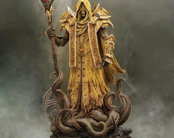 May include: A golden statue of a figure wearing a long, flowing robe and a hood. The figure is holding a staff with a red gem at the top. The statue is standing on a base with tentacles.