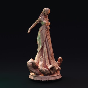 May include: A detailed sculpture of a woman in a flowing gown, with her eyes covered. The figure is standing on a base with a textured design. The sculpture is a light brown color and has intricate details.
