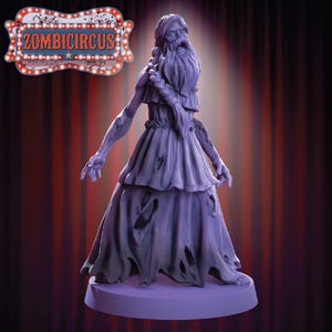 Puede incluir: Una figura morada de un personaje parecido a un zombi con un vestido andrajoso, una larga barba y los brazos extendidos. La figura está sobre una base redonda. El texto "ZOMBICIRCUS" se muestra encima de la figura.