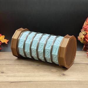 May include: A brown wooden cylinder with a combination lock. The lock has eight dials with numbers 1 through 9. The dials are light blue and the numbers are white.