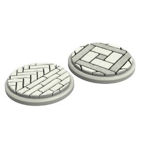 Puede incluir: Dos bases redondas, blancas, texturizadas, de piedra para juegos de miniaturas. Una base presenta un patrón de espiga y la otra un patrón de cuadrícula cuadrada.