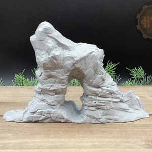 Puede incluir: Una formación rocosa blanca impresa en 3D con un arco natural. La roca está texturizada para parecer piedra.