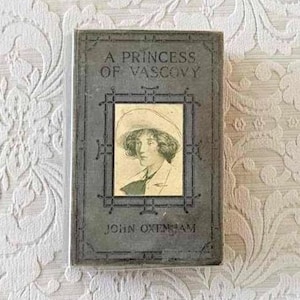 Puede incluir: Un libro vintage titulado "A Princess of Vascovy" de John Oxenham. La portada presenta una ilustración en blanco y negro de una mujer con un sombrero.