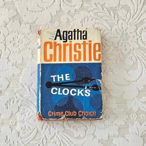 May include: A vintage paperback book titled "The Clock's" by Agatha Christie. The book cover features a blue background with a clock graphic and the words "The Clock's" in white. The author's name is in black and the title is in orange.