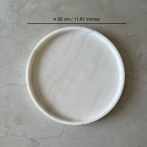 Pode incluir: Bandeja redonda de m&aacute;rmore branco, di&acirc;metro 30 cm.