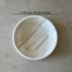 May include: A white marble bowl with gray veining. The bowl is 9.44 inches in diameter.