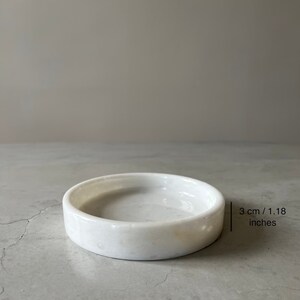 Pode incluir: Prato de m&aacute;rmore branco para bijuterias, com 3 cm de di&acirc;metro.