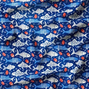 May include: A blue fabric with a repeating pattern of white fish and red seashells. The fish are stylized and have a simple design.