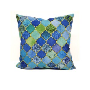 Peut inclure: Un coussin bleu et vert &agrave; motifs g&eacute;om&eacute;triques. Le coussin a un contour dor&eacute; et un effet aquarelle.