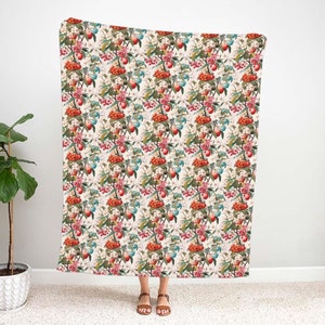 May include: A white throw blanket with a repeating pattern of red, green and blue fruit and flowers.