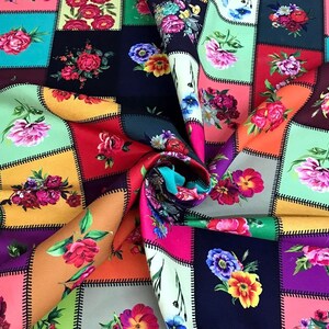 May include: A colorful floral fabric with a patchwork design. Each square features a different arrangement of roses, peonies, and other flowers in shades of pink, red, yellow, and purple. The fabric is folded, revealing a vibrant array of colors.