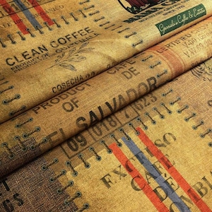 Puede incluir: Primer plano de una tela de arpillera marrón con texto impreso y detalles cosidos. El texto incluye "Clean Coffee", "Product of Guatemala" y "Product of Salvador". Se ven rayas rojas, azules y naranjas. La tela parece ser de sacos de café.