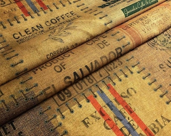 May include: Close-up of a tan burlap fabric with printed text and stitched details. The text includes "Clean Coffee," "Product of Guatemala," and "Product of Salvador." Red, blue, and orange stripes are visible. The fabric appears to be from coffee sacks.