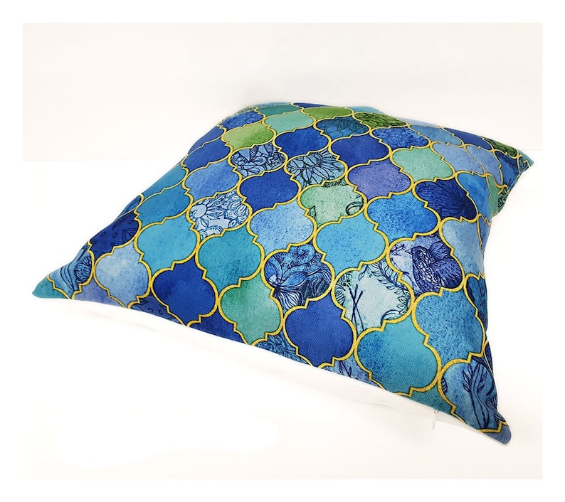 Peut inclure: Un coussin bleu et vert &agrave; motif g&eacute;om&eacute;trique. Le coussin a une bordure blanche et une fermeture &eacute;clair.