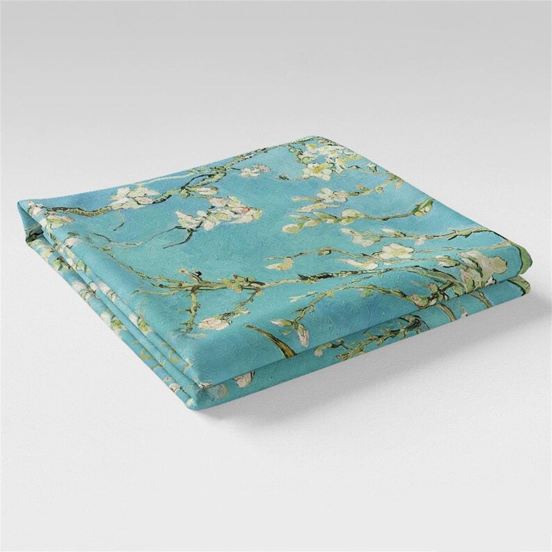 May include: A folded blue fabric with a white floral pattern. The fabric features a painting of blooming almond branches against a light blue sky.