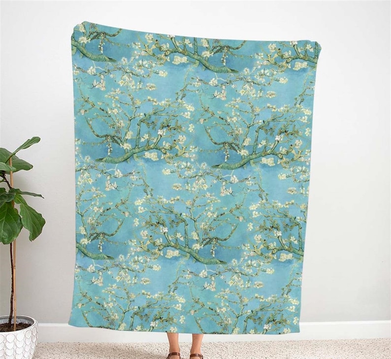 May include: A blue and white throw blanket with a repeating pattern of blooming almond trees. The pattern is inspired by a famous painting.