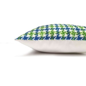 Peut inclure: Un coussin de d&eacute;coration avec un motif vert et bleu sur fond blanc. Le coussin est fait d'un tissu doux et tiss&eacute; et a un dos blanc.
