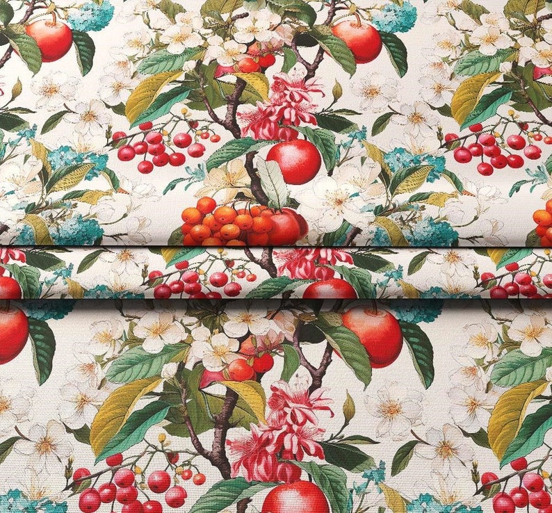 May include: A white fabric with a repeating pattern of red apples, red berries, and pink flowers. The background is a cream colour.