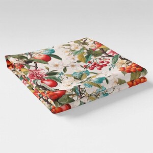 May include: A white fabric with a floral pattern featuring red apples, pears, and berries. The fabric has a vintage aesthetic and is perfect for crafting projects.