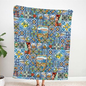 May include: A blue and white throw blanket with a colorful pattern of lemons, flowers, and geometric designs. The pattern is reminiscent of traditional Portuguese tiles.