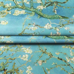 May include: A blue fabric with a repeating pattern of white blossoms and green branches. The fabric is folded in thirds, showing the pattern on each layer.