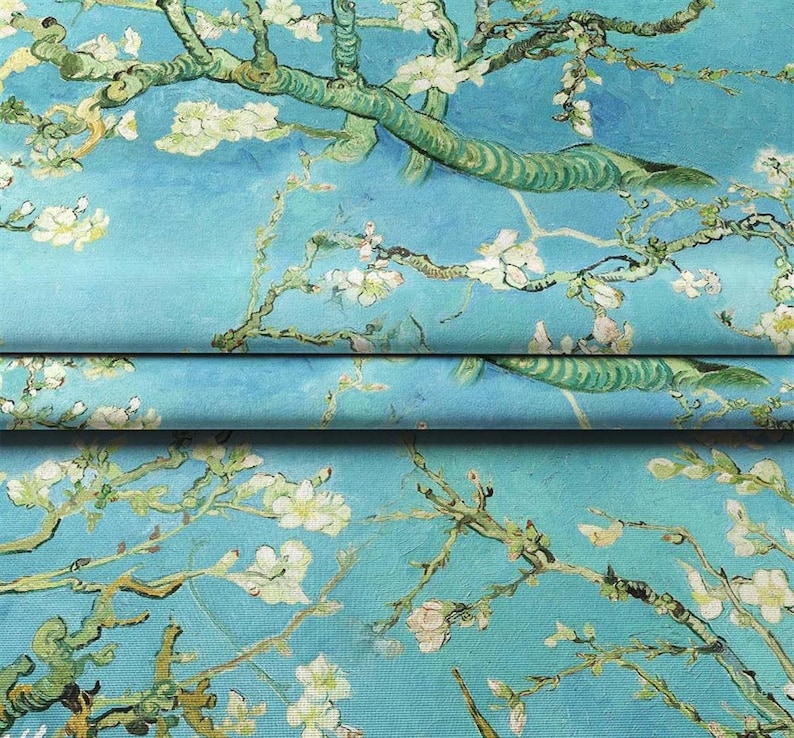 May include: A blue fabric with a repeating pattern of white blossoms and green branches. The fabric is folded in thirds, showing the pattern on each layer.
