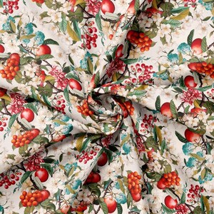 May include: A white fabric with a repeating pattern of red apples, green leaves, and red berries. The fabric is folded in the centre, creating a V-shape.