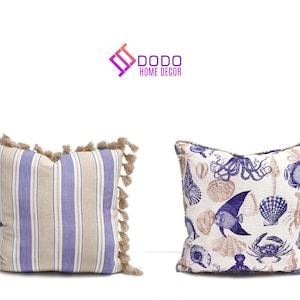 May include: Two decorative throw pillows. One features vertical stripes in lavender, beige, and white, with beige tassels. The other pillow has a nautical design with blue and beige sea creatures, including an octopus, fish, and seashells.