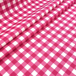 Könnte beinhalten: Rosa-weißes Gingham-Gewebe mit einem karierten Muster. Der Stoff ist in der Mitte gefaltet und das karierte Muster ist auf beiden Seiten sichtbar.
