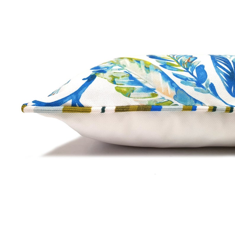 Peut inclure: Un oreiller blanc avec un motif floral bleu et vert. L'oreiller a une bordure blanche et une garniture ray&eacute;e bleu et vert.