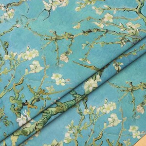 May include: A blue and white fabric with a repeating pattern of blooming almond branches. The fabric is folded in half, showing the pattern on both sides.