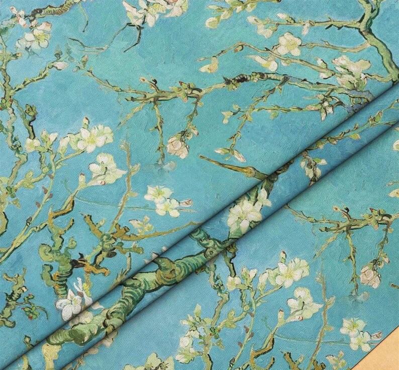 May include: A blue and white fabric with a repeating pattern of blooming almond branches. The fabric is folded in half, showing the pattern on both sides.