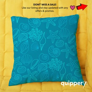May include: A turquoise blue throw pillow with a white outline of seashells, starfish, and coral. The pillow has the text "quippery" in white on the bottom right corner.