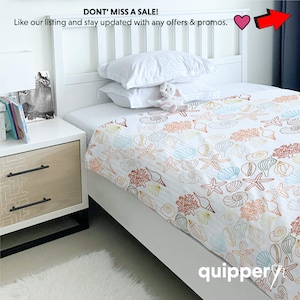 May include: White twin-sized bed with a white and orange seashell patterned bedding. The bed is in a bedroom with a white nightstand and a white rug.