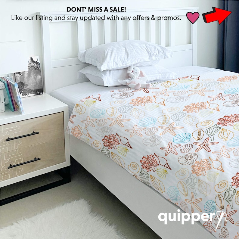 May include: White twin-sized bed with a white and orange seashell patterned bedding. The bed is in a bedroom with a white nightstand and a white rug.