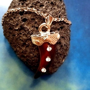 May include: A gold chain necklace with a pendant shaped like a brown and gold tooth with rhinestones.