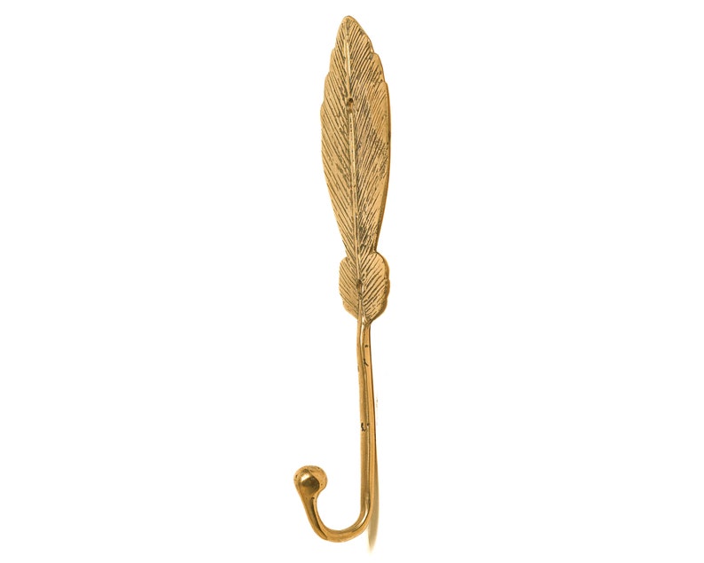 May include: A gold-colored metal hook shaped like a feather. The hook is designed to be mounted on a wall.
