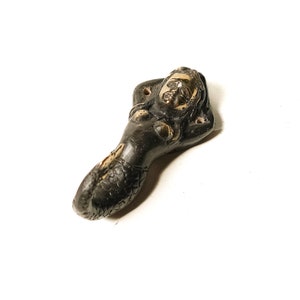 May include: A black and gold mermaid figurine with a long tail and a relaxed pose. The figurine is made of metal and has a detailed design.