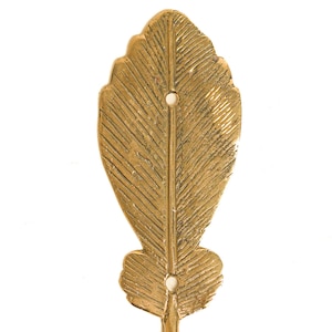 May include: Gold metal leaf-shaped wall hook with a textured surface. The hook has two holes for hanging.