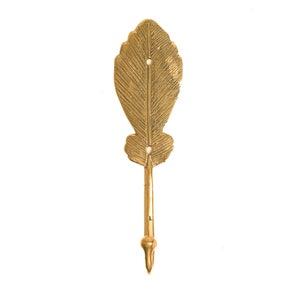 May include: A gold leaf-shaped hook with a textured surface. The hook is designed to hang items on a wall.