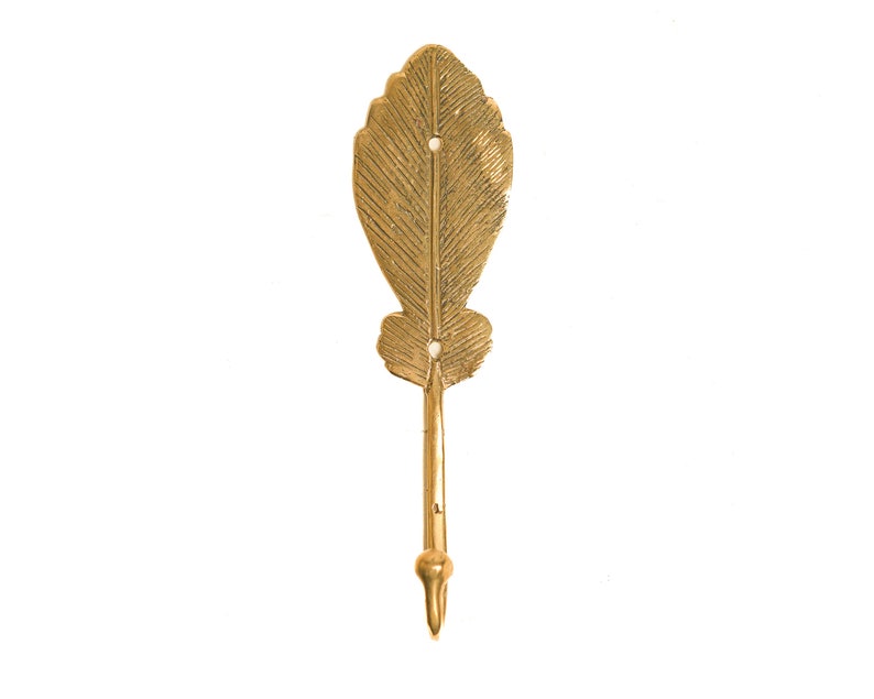 May include: A gold leaf-shaped hook with a textured surface. The hook is designed to hang items on a wall.
