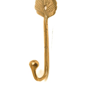 May include: A gold leaf-shaped hook with a decorative design. The hook is made of metal and has a simple, elegant design.